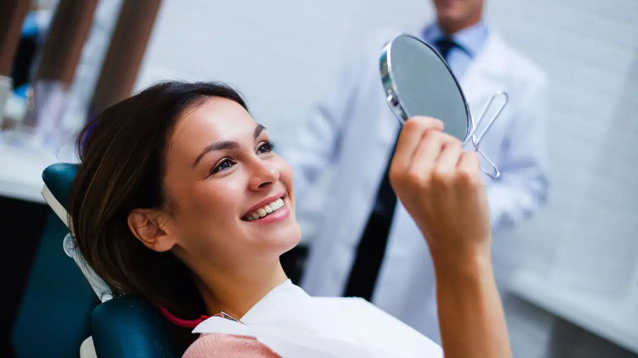 Woman looking at her new smile in a mirror